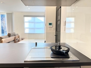 Ett modernt kök med en inbyggd spis, en kaffemaskin och ett fönster med utsikt över omgivningarna.