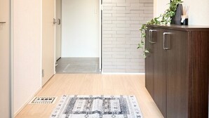 Un pasillo con piso de madera, un tapete estampado, un mueble con una planta y una pared con diseño de ladrillo.