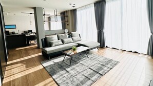 Una sala moderna con un sofá, una mesa de centro y un ventanal con cortinas.