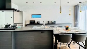Una cocina moderna con una isla central, electrodomésticos integrados e iluminación colgante.