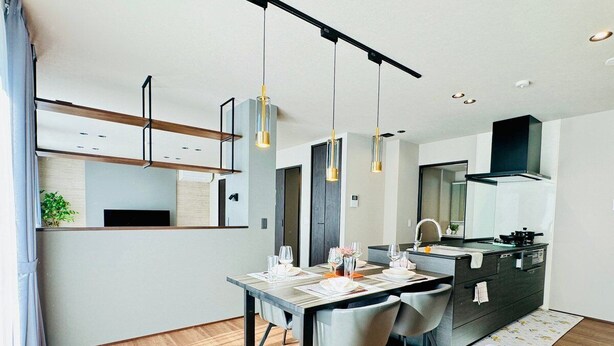 Una cocina moderna con comedor, piso de madera e iluminación colgante.