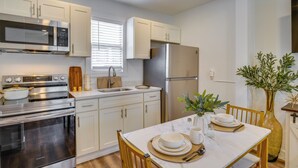 A modern kitchen with stainless steel appliances, white cabinetry, and a dining area with a marble table. - Gateway to Downtown Tacoma! Sleek Couple's Condo (Tacoma)