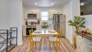 A compact kitchen with white cabinets, a microwave, a refrigerator, and a dining table with chairs. - Gateway to Downtown Tacoma! Sleek Couple's Condo (Tacoma)