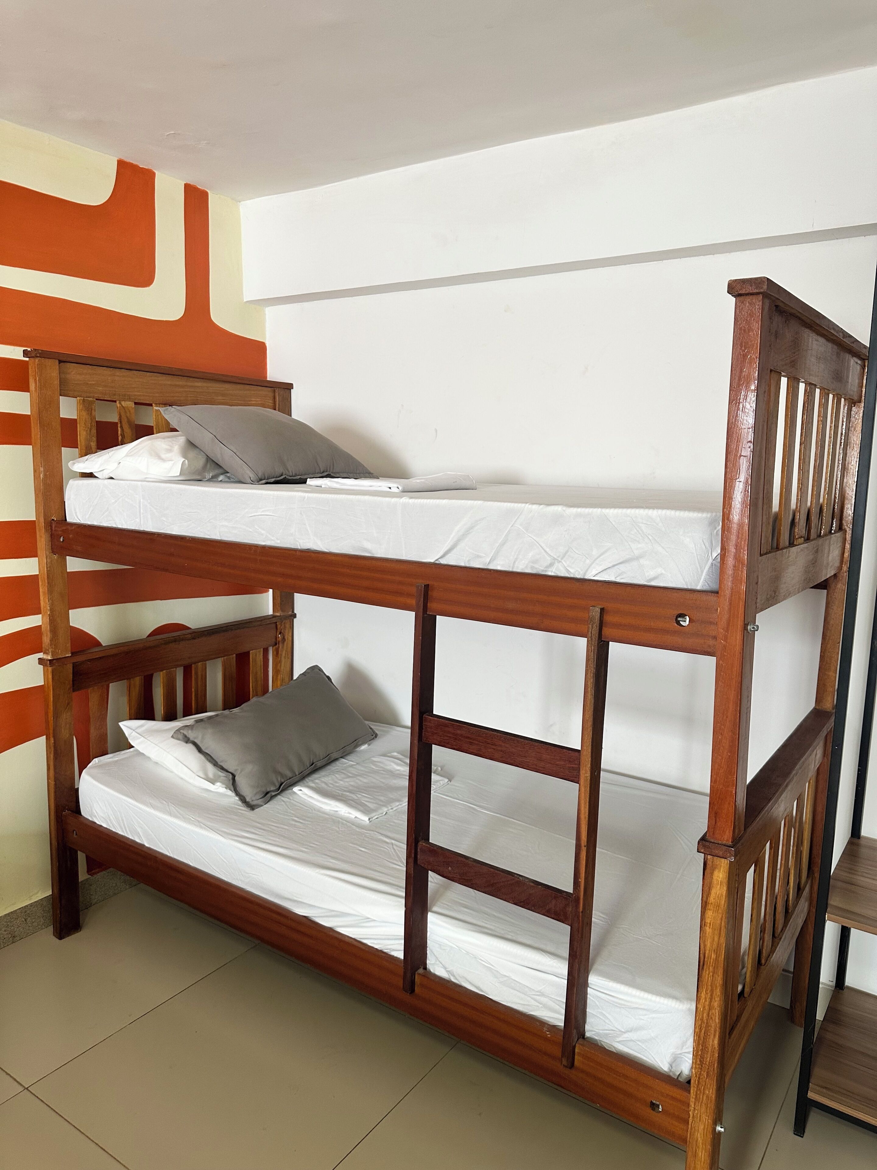 Una cama litera con dos plazas, cabecero de madera y almohadas grises.