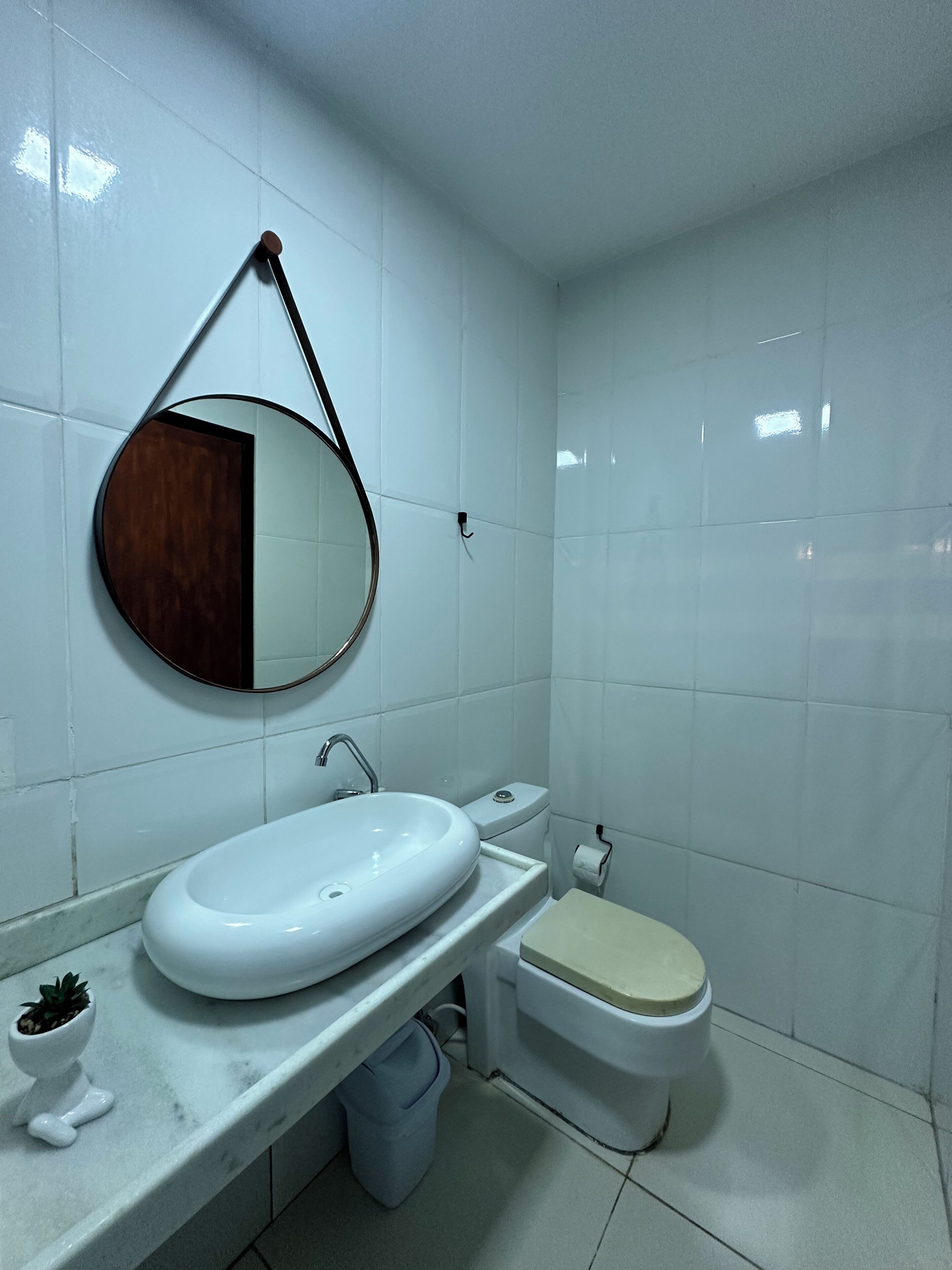Une salle de bain avec un lavabo blanc, des toilettes et un miroir doté d’un cadre en bois.