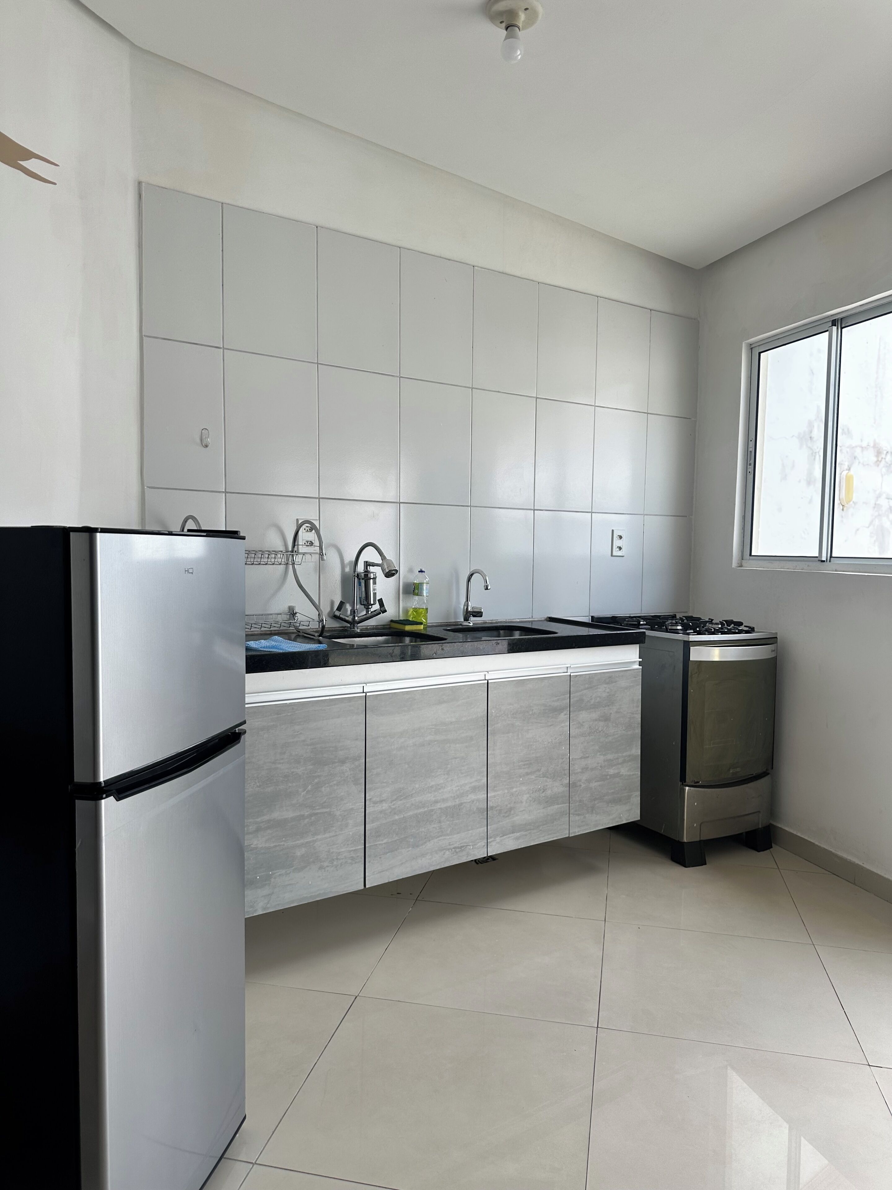 A modern kitchen with a refrigerator, sink, stove, and tiled backsplash.