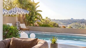 A poolside area with two sofas, a small table, and a potted plant. - Luxury Pacific Beach Hilltop Rooftop Deck, Pool, 14-Person Hot Tub, 6BR/5BA (San Diego)