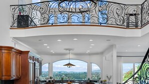 A spacious kitchen with a large island, a chandelier, and a view of the city. - Luxury Pacific Beach Hilltop Rooftop Deck, Pool, 14-Person Hot Tub, 6BR/5BA (San Diego)