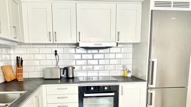A kitchen with white cabinets, a stainless steel refrigerator, a built-in oven, and a tiled backsplash. - Charming accommodation near station - 11 minutes to Liseberg (Västra Götalands län)