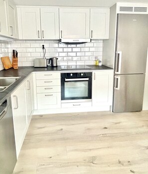 A kitchen with white cabinets, a stainless steel refrigerator, a built-in oven, and a tiled backsplash. - Charming accommodation near station - 11 minutes to Liseberg (Västra Götalands län)
