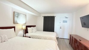 A hotel room with two beds, a TV on the wall, a door with a sign, and a wooden cabinet. - Awesome Oceanfront 1bd pool and hot tub (Myrtle Beach)
