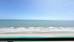 Ein Strand mit klarem Wasser und einigen Personen, die am Sand entlanggehen.