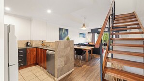 Une cuisine moderne avec un coin repas, un escalier et une vue sur l’extérieur.