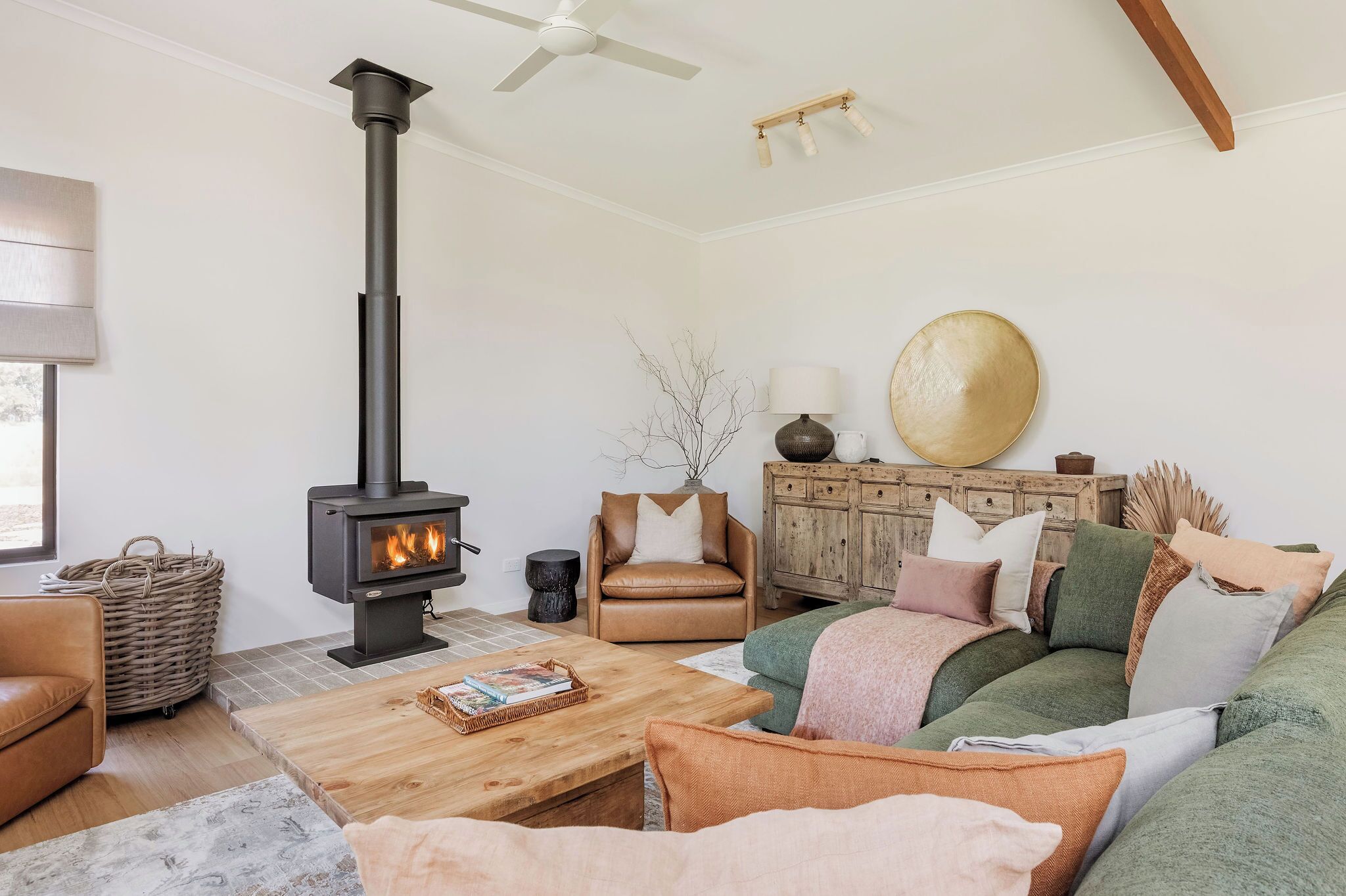Una sala de estar acogedora con chimenea, sofá de cuero, mesa de centro de madera y ventilador de techo.