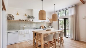 A kitchen with a wooden island, white cabinetry, and hanging wicker pendant lights.