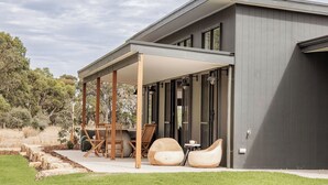 A modern house with a covered patio, outdoor seating, and a view of the surrounding landscape.