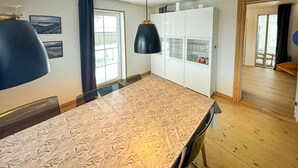Eine moderne Küche mit einer großen Kochinsel, Pendelleuchten und Blick ins Freie.