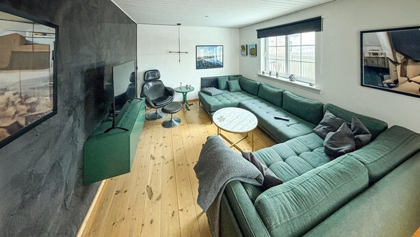 Ein modernes Wohnzimmer mit einem grünen Sofa, einem runden Couchtisch und einem großen Fenster.