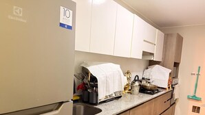 Moderni keittiö, jossa on valkoiset kaapit, graniittitaso, ruostumattomasta teräksestä valmistettu pesuallas ja liesi.