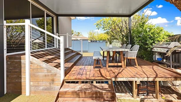 A covered outdoor patio with a table and chairs, a grill, and a staircase leading to an upper level. - Sasha's Cottage on the Hill | BBQ & Entertainment (Perth)