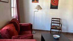 A living room with a red sofa, a wooden chair, a floor lamp, and two artworks on the wall. - Charming apartment in Avignon's historic center (Avignon)