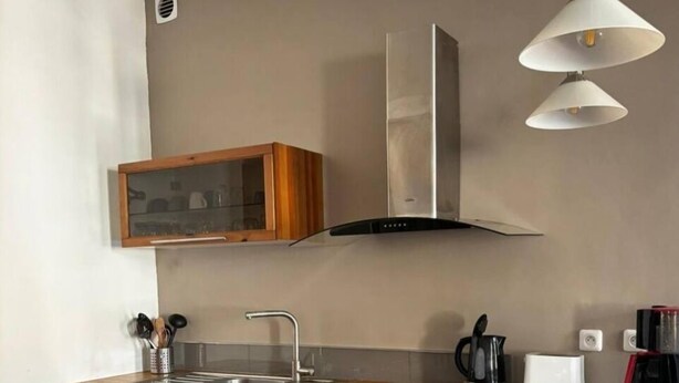 A compact kitchen with a dishwasher, sink, wooden cabinets, a stainless steel range hood, and pendant lighting. - Charming apartment in Avignon's historic center (Avignon)
