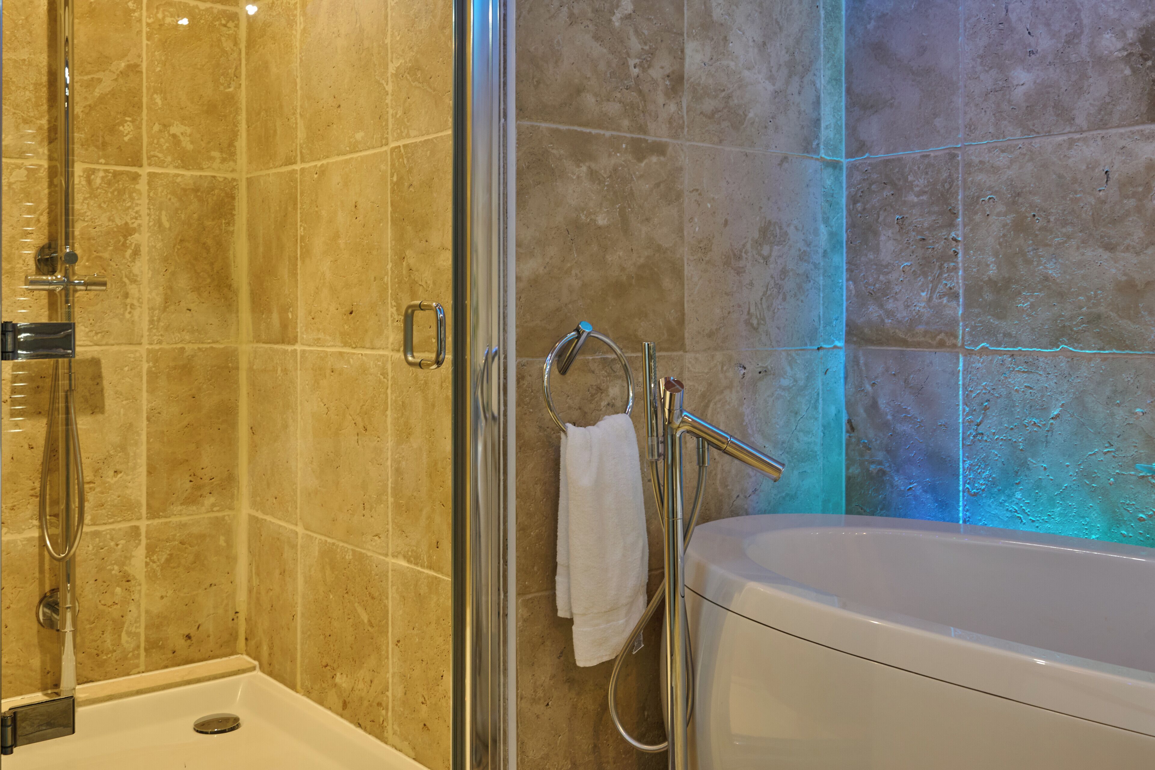 Un baño con ducha de vidrio, una bañera blanca y un perchero para toallas.