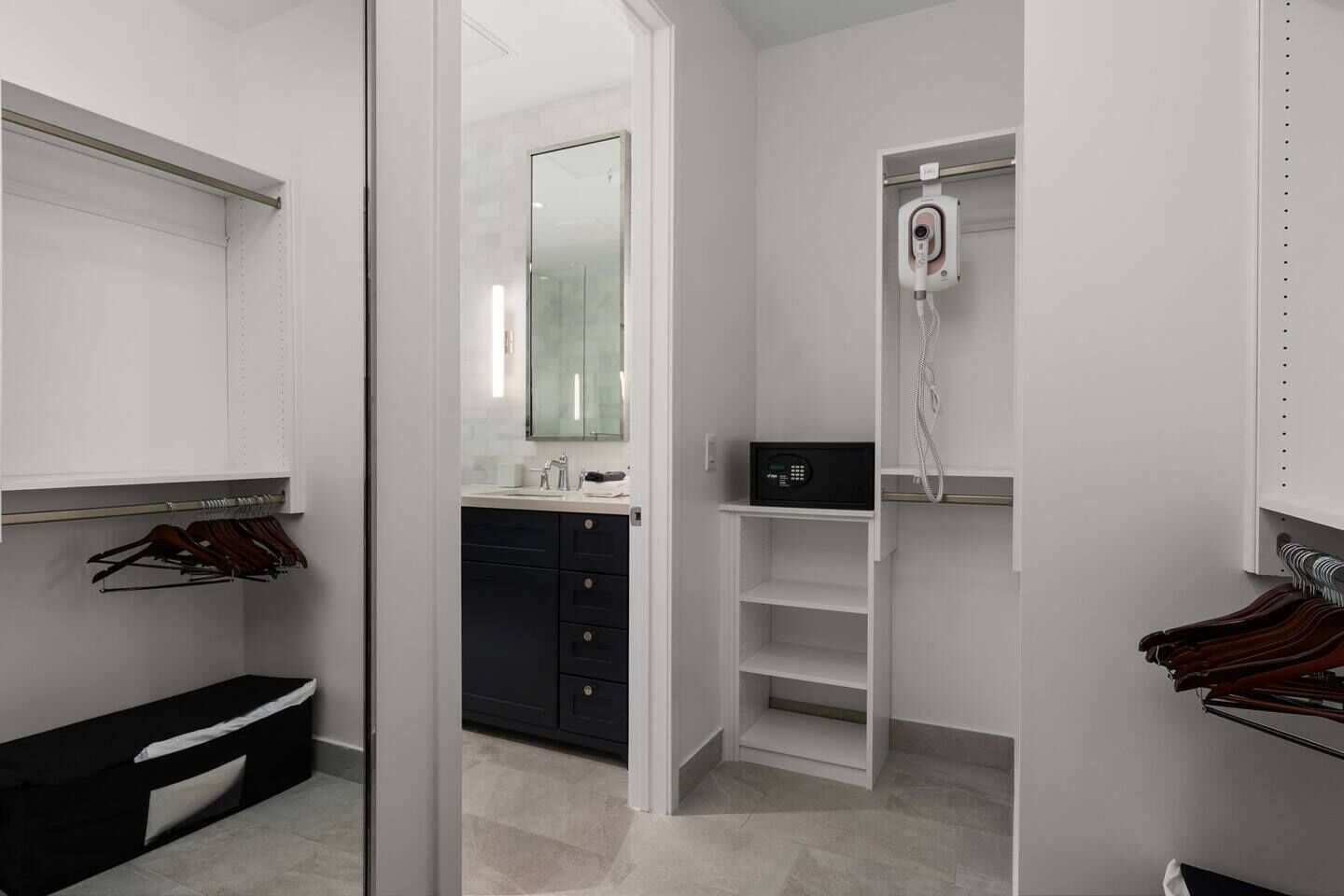 A modern bathroom with a glass shower enclosure, a vanity with a black cabinet, and a hairdryer mounted on the wall.