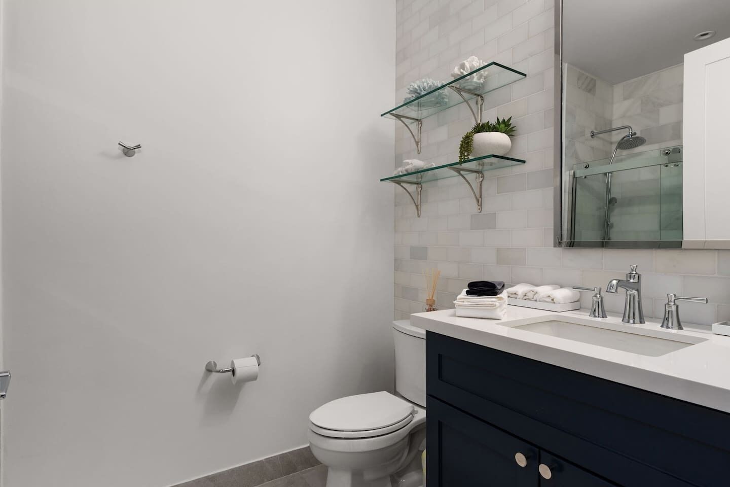 Et moderne badeværelse med toilet, håndvask med spejl og bruseniche.