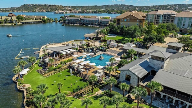 Ett flygbildsfoto av ett semesterkomplex med en stor pool, flera gästrum och en småbåtshamn.