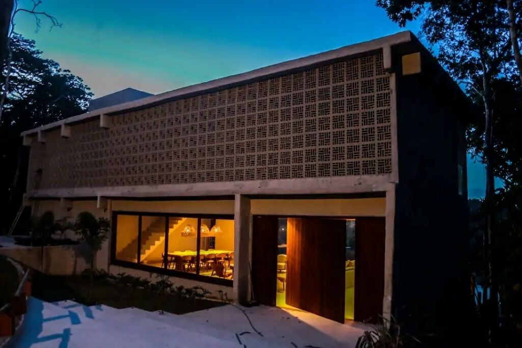 Un edificio moderno con tejado plano, amplias ventanas y una escalera que conduce a un nivel superior.