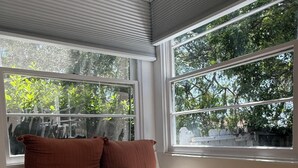 Une pièce d’angle avec un banc intégré, une petite boîte grise et un coussin rose et moelleux.