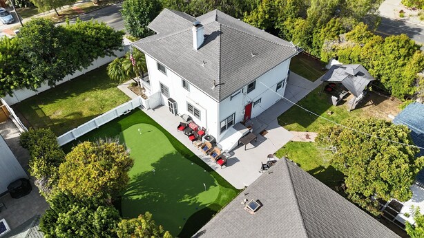 Une maison à deux étages avec un jardin devant, une petite piscine et du mobilier d’extérieur.