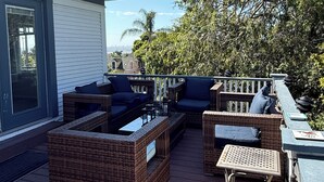 Une terrasse dotée de meubles en osier, d’une petite table et d’une chaise.