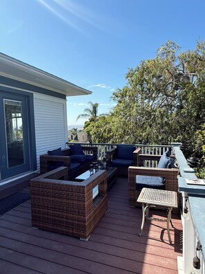 A deck with wicker furniture, a small table, and a chair. - Historic Pacific Beach Home with Putting Green, Jacuzzi, and Pool Table (San Diego)