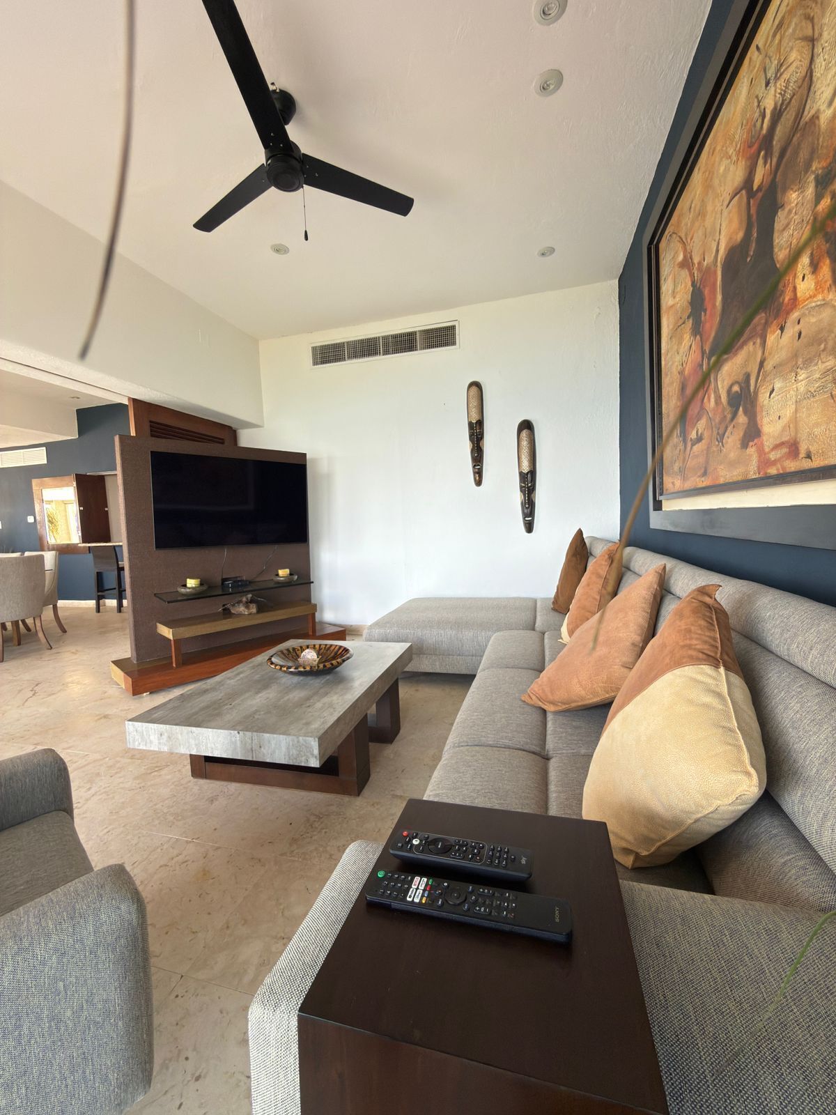 Ein modernes Wohnzimmer mit Sofa, Couchtisch, Fernseher und Deckenventilator.