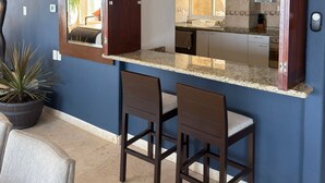 A kitchen with a dark blue wall, a countertop, and two chairs. - Luxury villa with ocean view and private pool. Expectacular | 10 guests (Acapulco de Juárez)