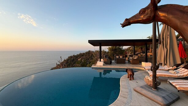 A swimming pool with a clear view of the ocean, a statue, and outdoor seating. - Luxury villa with ocean view and private pool. Expectacular | 10 guests (Acapulco de Juárez)