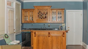 Una cocina con armarios de madera, una alacena para vinos, un lavamanos y una puerta.