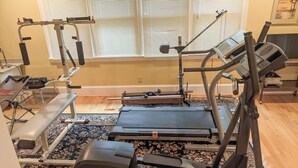 Un gimnasio en casa con una cinta de correr, banco de pesas y diversos equipos de ejercicio.