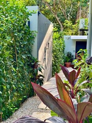 A garden area with a concrete structure, possibly a shower or water feature, surrounded by lush greenery and potted plants. - Private Tropical Villa in Marbella, Modern Comfort Just Minutes from the Beach! (Provincia de Guanacaste)