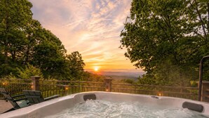 Ein Whirlpool mit Blick auf einen Sonnenuntergang und umliegende Bäume.