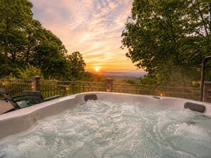 Ein Whirlpool mit Blick auf einen Sonnenuntergang und umliegende Bäume.