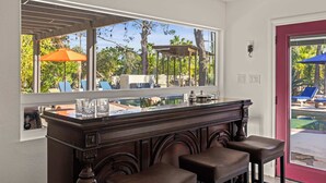 Eine Bar mit großem Fenster, Blick auf einen Pool und einer roten Tür.