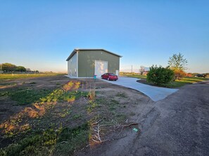 Ein eingeschossiges Gebäude mit Garage, befestigter Auffahrt und einem roten Auto davor.