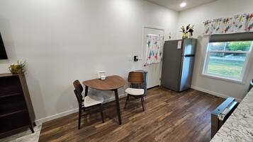 A compact kitchen with a dining table, chairs, a refrigerator, and a window with a view.