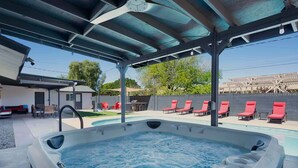 A hot tub with a covered patio area, outdoor seating, and a view of a pool. - Casa Mesa • Private Paradise w Pool, Putt, & Games (Mesa)
