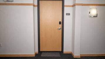 A hotel room entrance with a wooden door, a number '307' on the wall, and a wall-mounted light fixture.