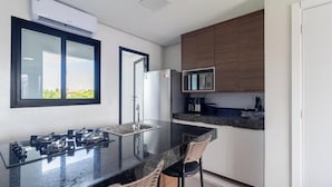A modern kitchen with a gas stove, a microwave, and a refrigerator. - Modern Apartment in a Condo With Pool Rnm0015 (Porto Seguro)