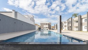 A swimming pool with a modern design, surrounded by contemporary buildings. - Modern Apartment in a Condo With Pool Rnm0015 (Porto Seguro)